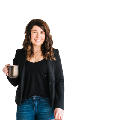 A woman in a black blazer and blue jeans holds a coffee cup