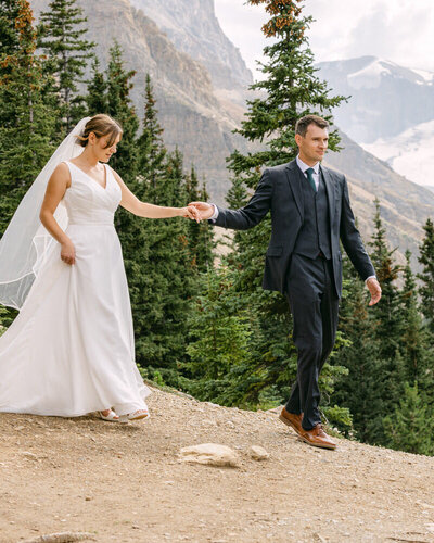 This breathtaking photograph captures the groom holding the bride’s hand during their mountain helicopter wedding, with a stunning glacier in the background. The majestic landscape and intimate connection between the couple make this an unforgettable and dramatic moment.