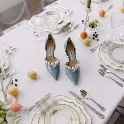 A pair of blue Jimmy Choo pumps arranged on a reception table decorated with colorful fruit. Photo by documentary photographer Haley Hawn.