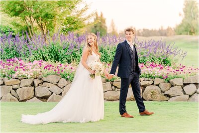 Bride and groom walking with colorful flowers at Langdon Farms