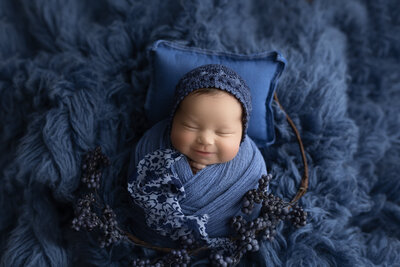 baby smiling in blue, newborn wrapped