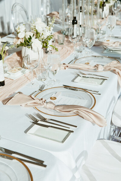 This image captures beautifully arranged place settings and centerpieces on long tables, showcasing an elegant wedding setup. Each setting features refined details, including stylish tableware and stunning floral arrangements, perfect for enhancing any event. Ideal for couples planning their Ottawa weddings, this photo illustrates our expertise in creating memorable dining experiences with a focus on modern design elements.