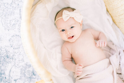 baby with bow on her head smiling at camera in-home Tampa newborn photography session.