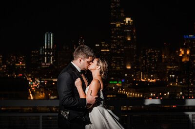 Bride and groom kiss in front of the Chicago skyline at night