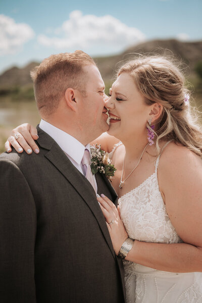 A bride and groom go in for a kiss in the summer sun.