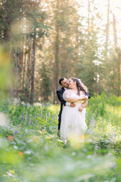 Couple bride and groom eloping at Yosemite National Park Taft Point hike during summer with colorful lupine wildflowers.