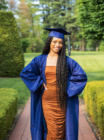Senior girl wearing a brown fitted short dress, and  graduation cap and gown