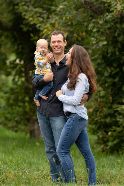 Family of mother and father standing holding one year old baby boy