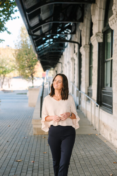 Jenn walking down a brick lined sidewalk, smiling