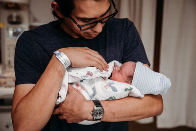 mom and dad snuggling their new baby in her nursery in Fort Collins Colorado