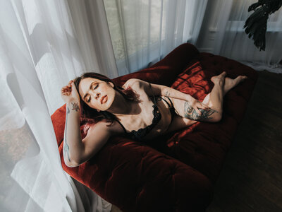 woman posing on red sofa during boudoir shoot