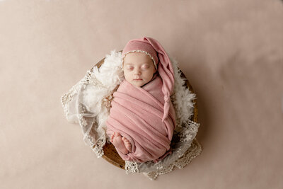 Newborn baby girl on a pink background with a pink flower headband