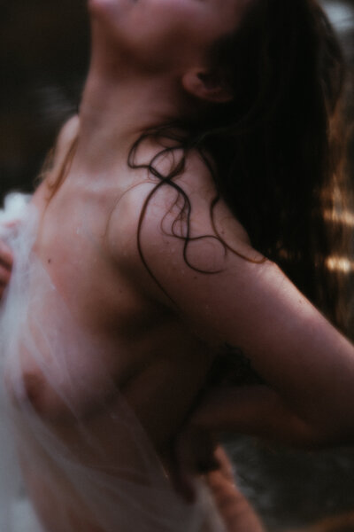 woman in a river with a sheer white drape covering her body