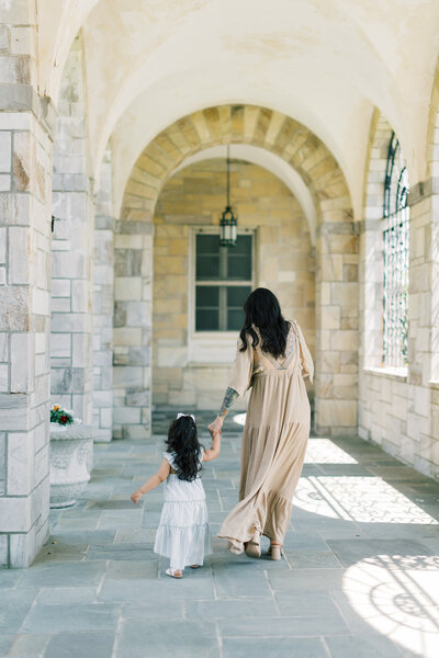 Mother and daughter walk hand in hand during their family portrait session