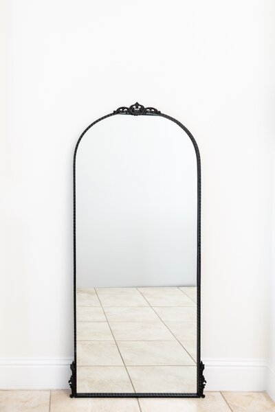 Black arched mirror with decorative top detail on stand