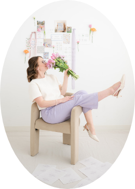 Margit sits in a chair with her legs kicked up, smelling a bouquet of pink tulips