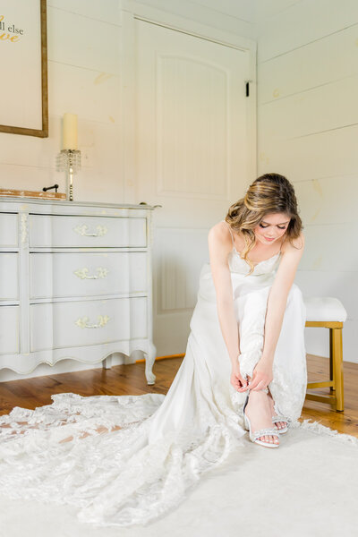 bride in white dress putting shoes on in getting ready space at the granary wedding venue
