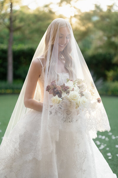 Bride in wedding dress walking down outdoor aisle with groom in tuxedo