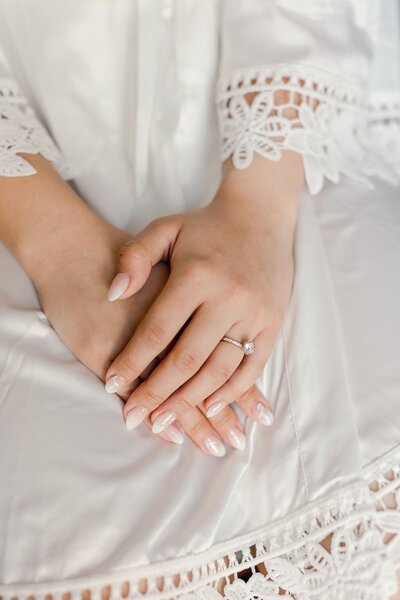 Bride holding hands in lap getting ready robe