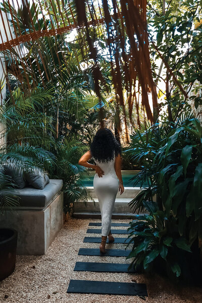 Woman walks through tropical area in white dress