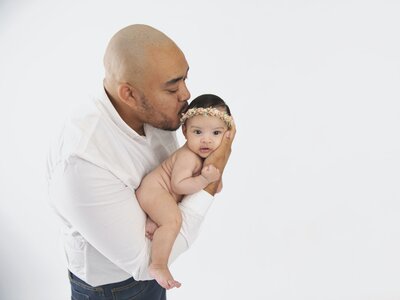 Dad kissing newborn baby