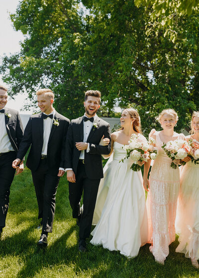 bride and groom smiling and walking with their friends