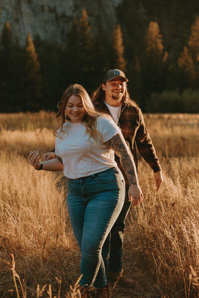 Couple holding hands and laughing in Yosemite Valley during their Yosemite engagement session