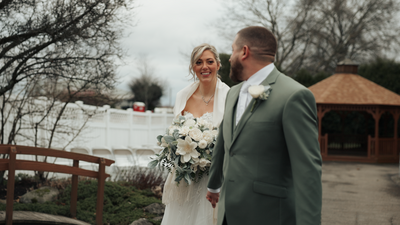 couple in wedding attire leaning against an old rusty car