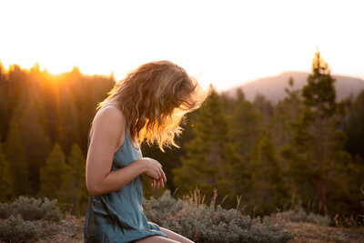 Woman kneels in a lingerie night dress with the sun streaming through her windblown hair