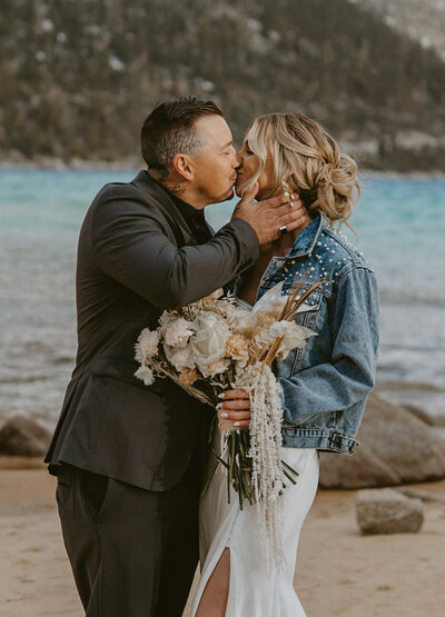 Wedding couple kissing on the beach in Lake Tahoe after sharing in an intimate wedding celebration.