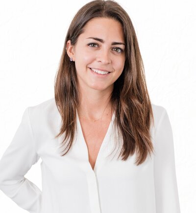 Alivia Hall, founder of LiteMinded Therapy in NYC, wearing a white shirt and jeans, smiling warmly.