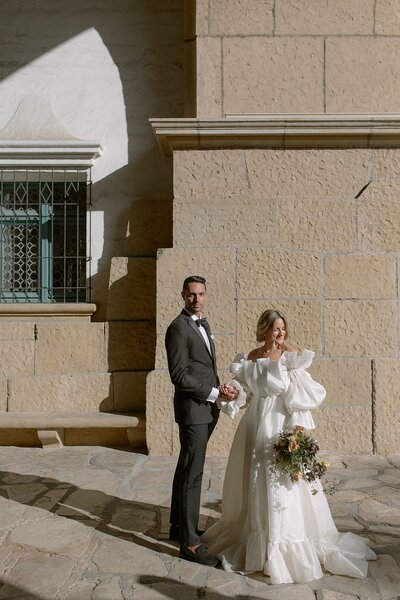 Groom covers his eyes as he sees his beautiful bride on their wedding day at San Juan Capistrano Mission