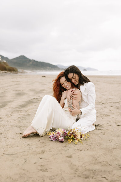 Two brides embrace after getting married on a beach in Nova Scotia. 