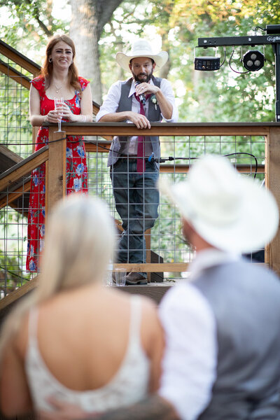 An Austin-based man in a cowboy hat is giving a speech at a wedding.