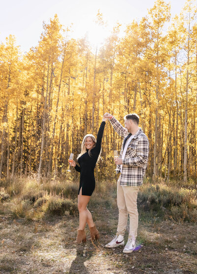 a couple dance around and laugh while sipping champagne at pine cree cookhouse
