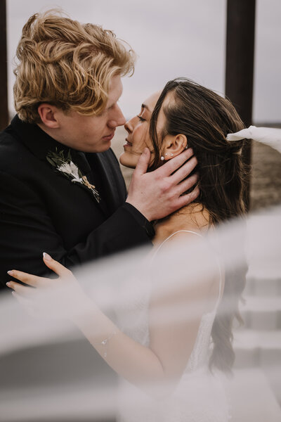 Engaged couple leaning for a kiss.