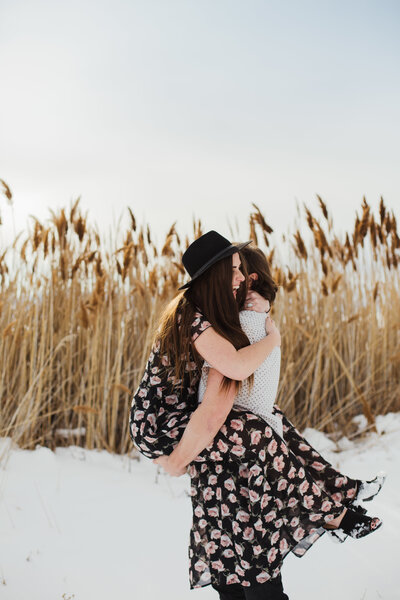 couple hugging and laughing in the winter during outdoor engagement session