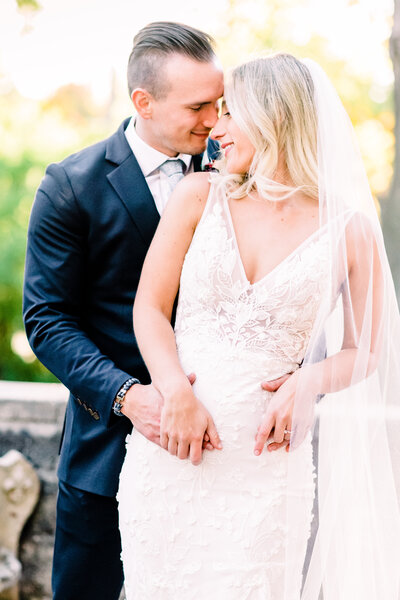 Groom hugging bride nose to nose with long veil at sunset by Grand rapids wedding photographer Stephanie Anne