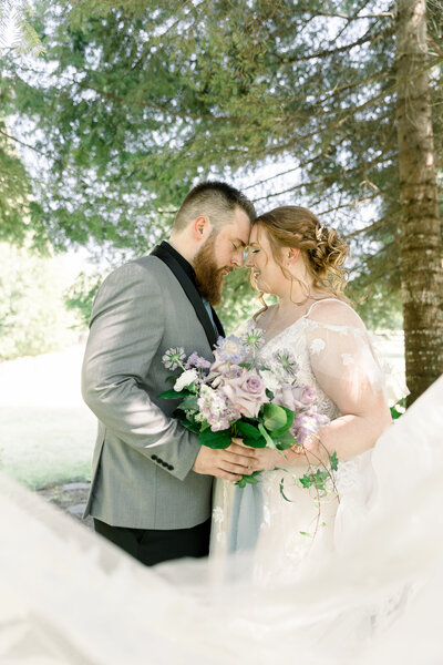 bride and groom closing eyes touching foreheads while holding flowers  taken by Spokane Wedding photographer