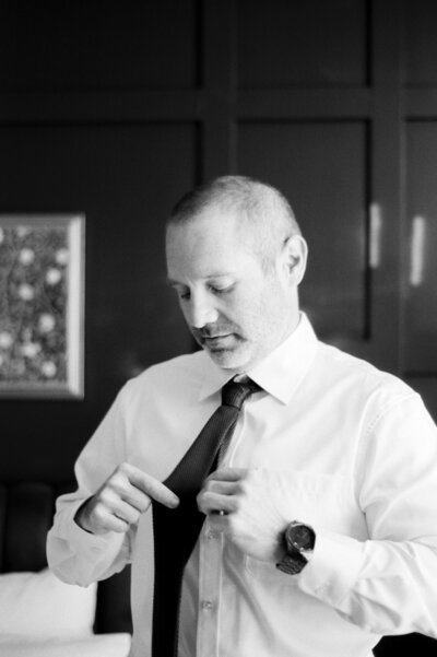 Groom putting on tie getting ready