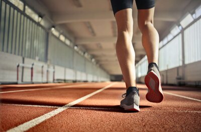 woman wearing tennis shoes running on track