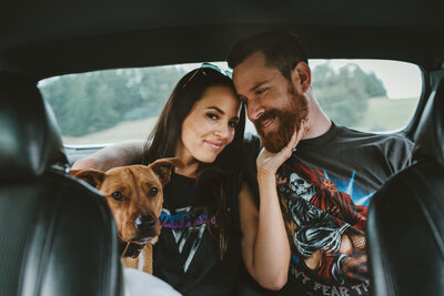 woman and man sitting in the back of a car with their dog
