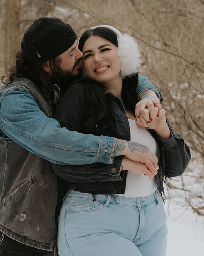 a close up photo of a couple where the man is embracing the woman from behind and they are laughing. photo by dash and boheme photography 