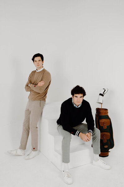 two men posing in a studio with golf gear