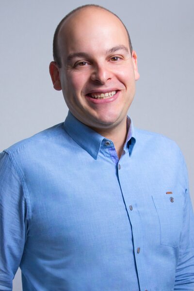 Startup advisor Darren Berkovitz smiling in blue button-up shirt