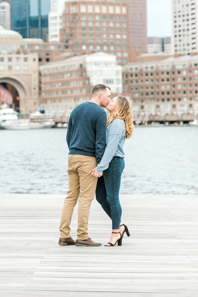 engaged couple kissing beside water