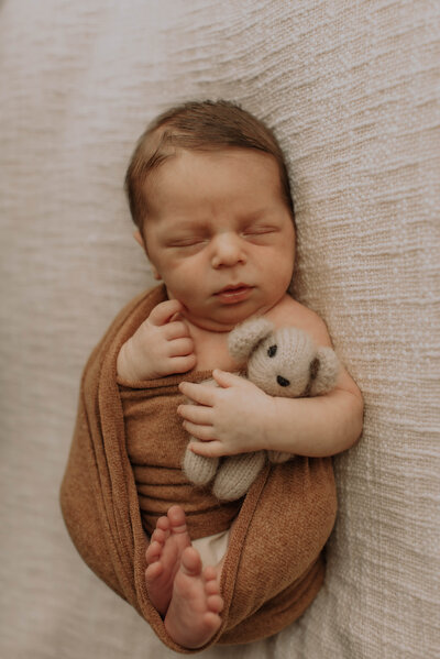 Pasgeboren baby in wikkeldoek slaapt tijdens newbornshoot
