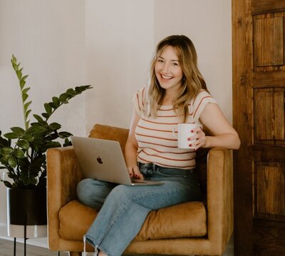 Ali sitting in chair with laptop and coffee