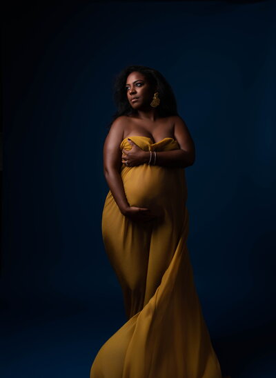 Los Angeles Luxury Maternity Photographer - Mom draped in gold fabric on blue backdrop