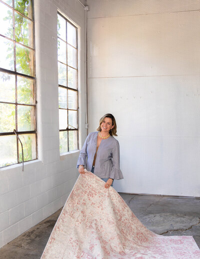 photo of a woman holding a carpet with windows behind her